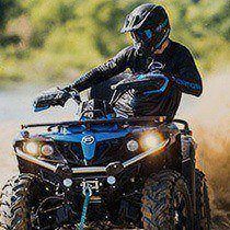 Man in a dark helmet rides a blue ATV.